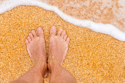 Relaxing on the ocean beach, feet on the sea sand. bare feet on a sandy beach with waves and foam.
