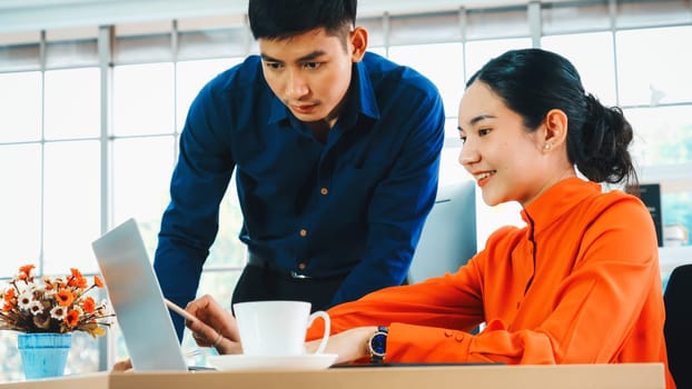 Two business people talk project strategy at office meeting room. Businessman discuss project planning with colleague at modern workplace while having conversation and advice on financial report. Jivy