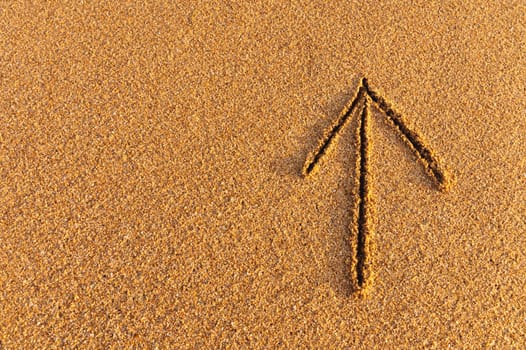 Drawn arrow on the sand. drawing of an arrow sign pointing up, path direction.