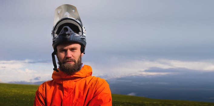 Portrait of a racer in full protection of a full face mask on a bicycle or motorcycle in the summer mountains. The concept of attracting youth to outdoor sports.