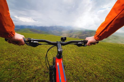 Point of view of a mountain biker riding in difficult terrain. hands and cyclist in nature overlooking the mountains. adventure and cardio workout idea.