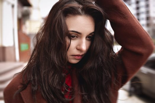 Portrait of an very upset woman in an autumn coat on the street touches her head. frustrating and depression concept