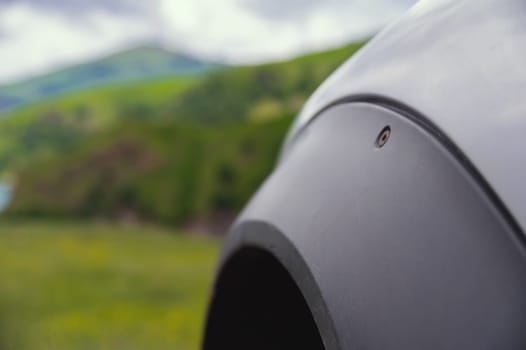 wheel under the fender of an SUV, extreme off-road ride, close-up of the fender of a clean car. green mountains can be seen in the background.