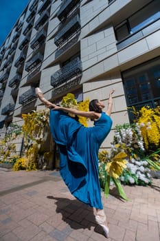 Beautiful Asian ballerina posing against the backdrop of a building decorated with flowers