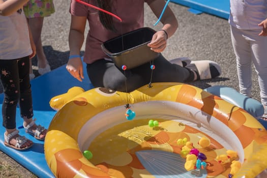 Girls catch rubber ducks with fishing rod in a park