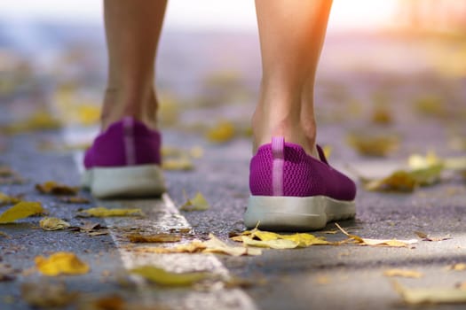 Pair of violet female, sneakers in autumn foliage. Selective focus