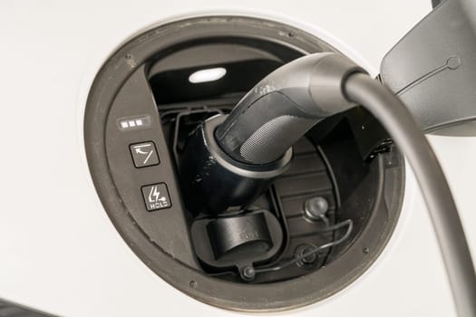 Level 2 240V home charging with J1772 plug inserted into the port of modern electric car to recharge battery