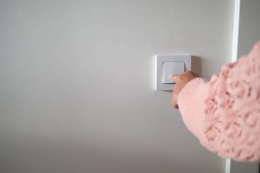 A hand gently pressing down on a light switch in a warm and cozy home setting ambiance