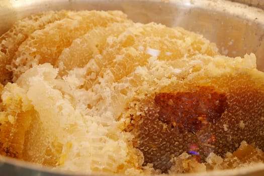 Fresh honeycomb pieces are stored in stainless steel pots, perfect for culinary applications