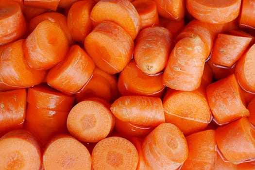 Vibrant orange carrot slices are submerged in clear water, showcasing their vivid color