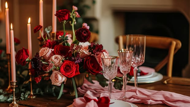 Festive table setting with candles and arrangement of beautiful red flowers. Holiday concept. High quality photo