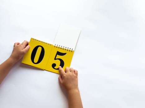 A child turns a page of learning numbers to the next number on a bright yellow background.
