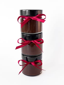 Homemade chocolate spread jars with red ribbon on white background.