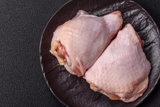 Fresh raw chicken thighs with salt and spices on dark concrete background