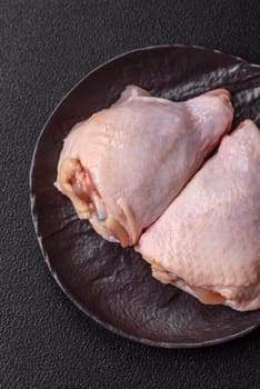 Fresh raw chicken thighs with salt and spices on dark concrete background