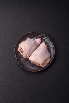 Fresh raw chicken thighs with salt and spices on dark concrete background