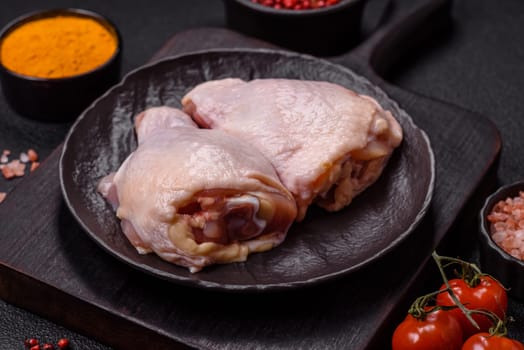 Fresh raw chicken thighs with salt and spices on dark concrete background