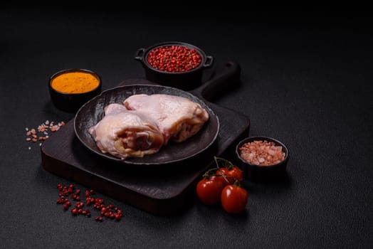 Fresh raw chicken thighs with salt and spices on dark concrete background