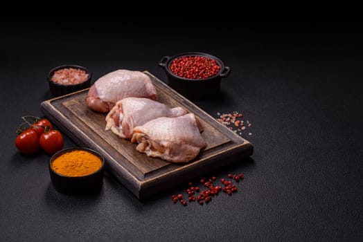Fresh raw chicken thighs with salt and spices on dark concrete background