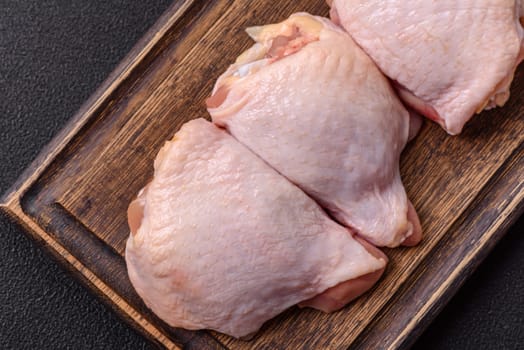 Fresh raw chicken thighs with salt and spices on dark concrete background