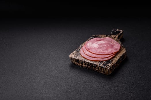 Boiled ham with salt and spices cut into slices on dark concrete background
