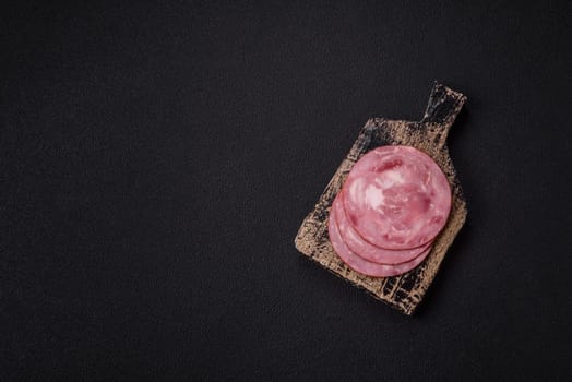 Boiled ham with salt and spices cut into slices on dark concrete background