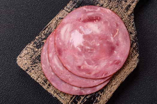 Boiled ham with salt and spices cut into slices on dark concrete background
