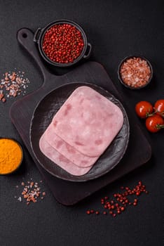 Boiled ham with salt and spices cut into slices on dark concrete background