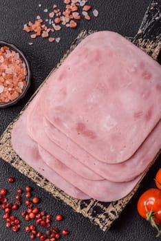 Boiled ham with salt and spices cut into slices on dark concrete background