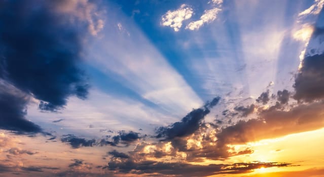 beautiful orange sunset on a blue sky with clouds. A wide panorama of the sky with sunlight at sunrise