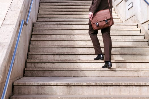 crop of the legs of unrecognizable stylish mature businessman in classy suit with briefcase walking up urban stairs in city, concept of business and middle age man lifestyle, copyspace for text