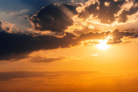 orange sunset with sunlight on cloudy sky. Background with sky with clouds in summer