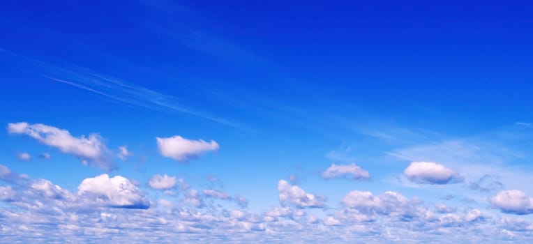 background of blue sky with white fluffy cumulus clouds. Panorama of the sky