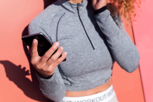 close up of the hand of an anonymous female athlete using cellphone, concept of technology of communication and modern lifestyle