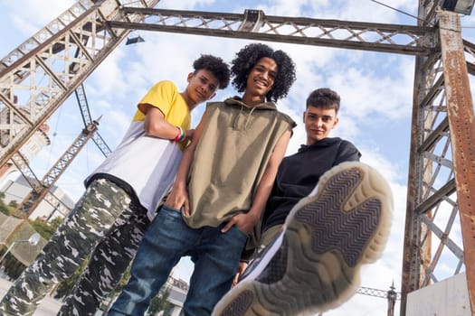 from below of three diverse teenager friends doing kick and looking at camera challenging, concept of youth and urban lifestyle