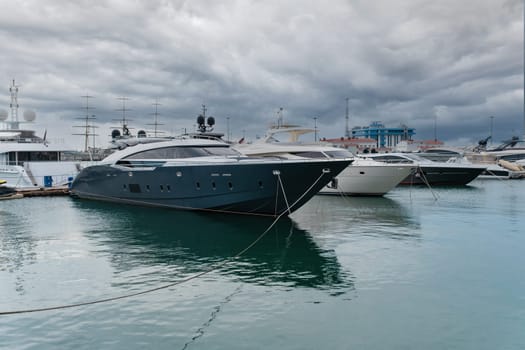 Yachts docked at a marina under overcast skies near a coastal city - Sochi, Russia April 14, 2023.