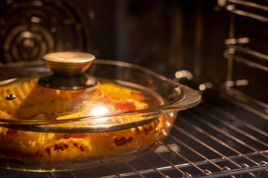 Vegetables baking in the transparent dish in the oven.