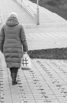 Woman with plastic bag and hash tag illustration on it walks outdoor