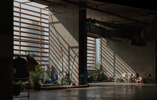Bangkok, Thailand 05 Jan, 2025 - Morning sunlight shines through Wooden Battens to The washing area for maid and Variety of Chairs near concrete wall on parking lot of Condominium building. use it as your Wallpaper, Poster and Copy space, Selective focus.