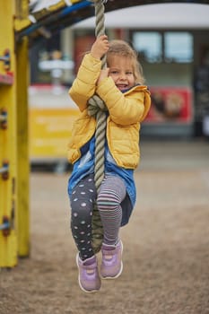 Charming child climbs a rope at a playground in Denmark.