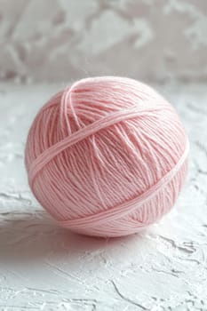 A pink ball of wool yarn standing out against a white background.