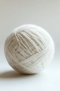 a white ball of wool yarn standing out against a white background.