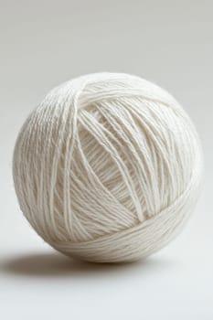 a white ball of wool yarn standing out against a white background.