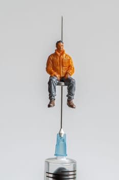 The man is on a needle. A drug addict in a medical syringe with a needle on a white isolated background. The concept of combating drugs.