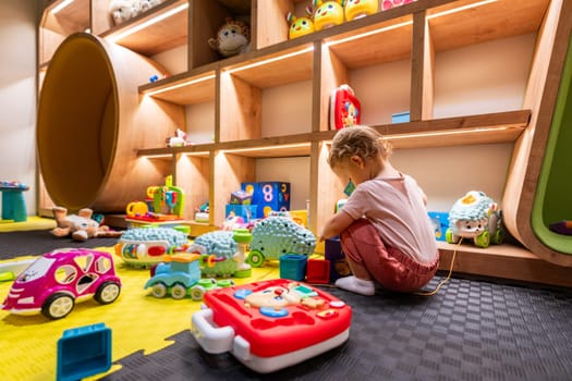 A cheerful little girl surrounded by colorful toys in a vibrant playroom. Concept of imaginative play and joyful learning