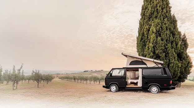 Modern camper van parked in the countryside, offering a luxurious and comfortable way to explore nature. The van features a sleek black exterior, wooden accents, and a spacious interior
