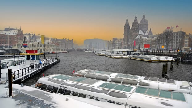 Snowy city Amsterdam in the Netherlands with the St. Nicolas church in winter at sunrise