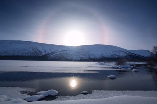 beautiful arctic snowy landscape with frozen lake, solar halo phenomenon,