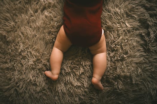 Adorable baby legs on fluffy brown bed coat. Babyhood and parenting concept. High quality photo