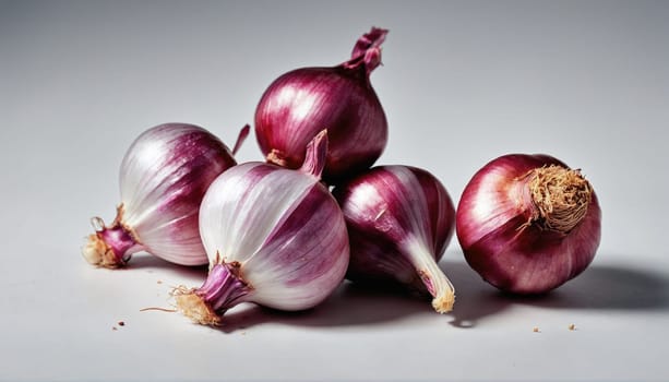 A collection of fresh red and white onions is arranged on a light surface, highlighting their glossy skin and unique shapes. The onions are visually appealing and ready for culinary use.